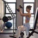 An image of woman raising dumbbells