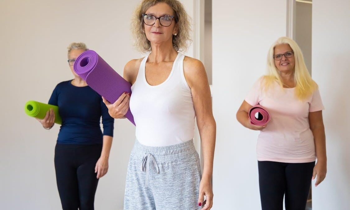 An image of women holding yoga mats for a group workout class