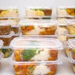 Multiple meal prep containers with rice, vegetables, and protein prepared for the week