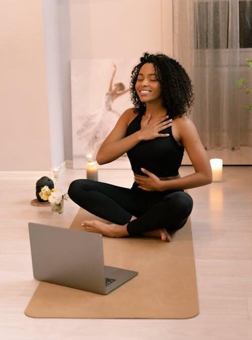 Woman practicing yoga at home following an online fitness class on a laptop
