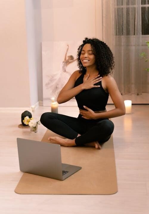 Woman practicing yoga at home following an online fitness class on a laptop